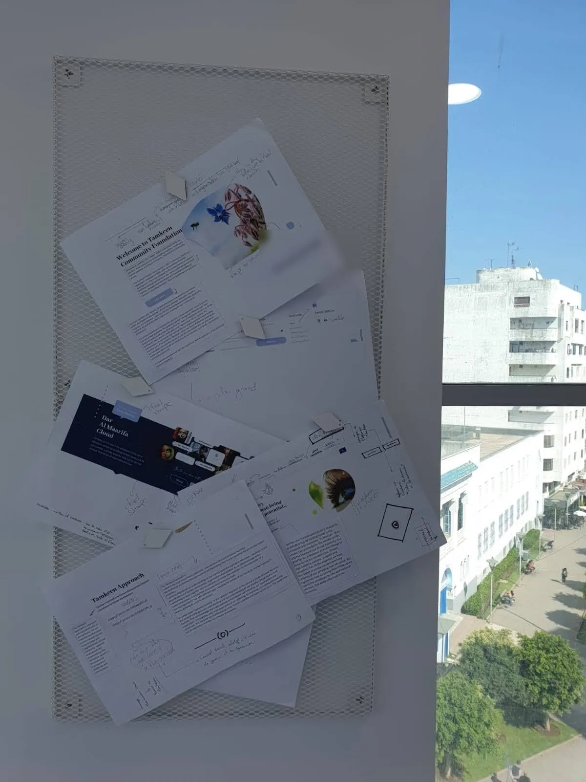 Des maquettes de site imprimées et annotées, épinglées au mur du bureau